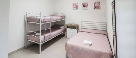 Dormitorio con literas, una cama individual, una mesita de noche y tres cuadros colgados en la pared.