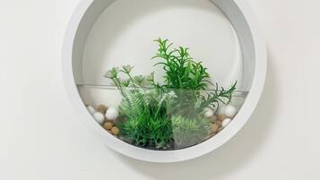 Un acuario redondo blanco fijado a la pared, con plantas acuáticas verdes y guijarros.