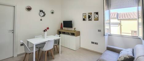 Ett kompakt bostadsutrymme med en matplats, en tv och en soffa.