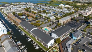 An aerial view of a coastal hotel with multiple buildings, a marina, and a large swimming pool. - Great Location for Sunday Fireworks and Easy Walk to the Beach! Has a Pool! (Ocean City)