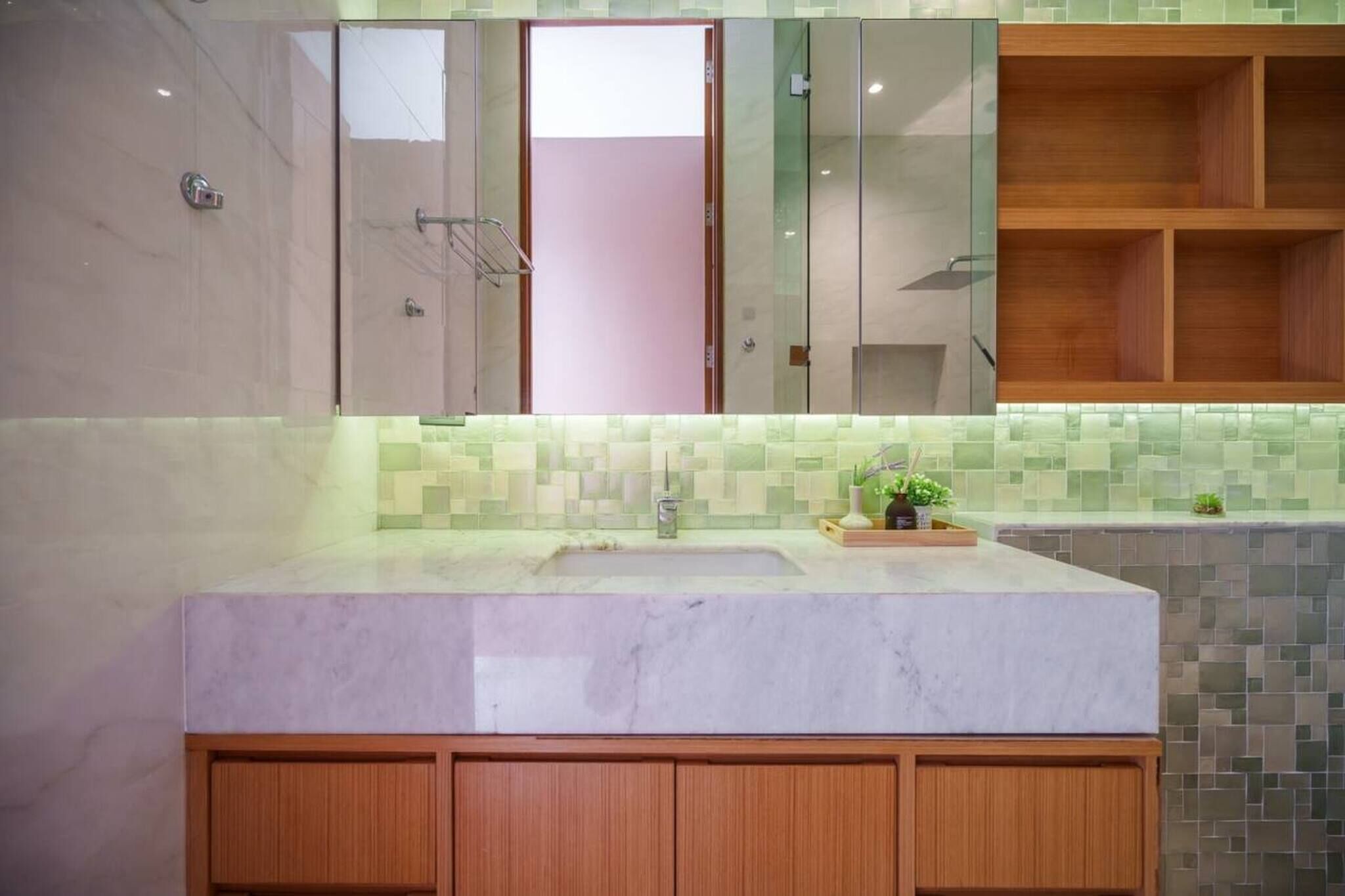 Un baño con lavamanos de mármol, un espejo y un salpicadero de azulejos.