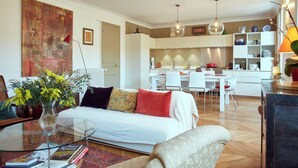 A modern living room with a sofa, a glass coffee table, and a dining area with a white table and chairs. - Marvelous 2-bedroom apartment in Paris perfect for your getaway (Paris)