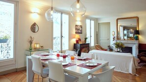 A dining area with a white table set for four, two pendant lights, a fireplace, and a large mirror. - Marvelous 2-bedroom apartment in Paris perfect for your getaway (Paris)