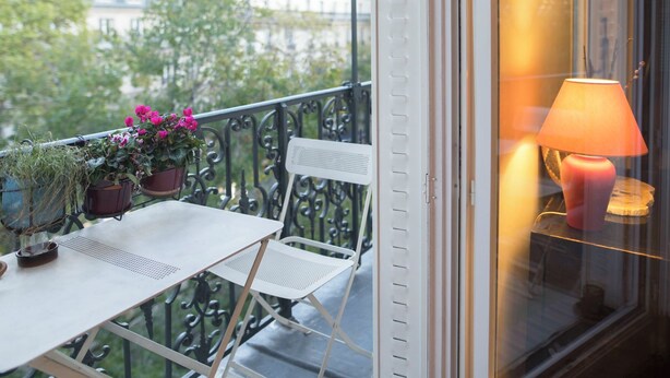 A balcony with a table, chairs, potted plants, and a lamp. - Marvelous 2-bedroom apartment in Paris perfect for your getaway (Paris)