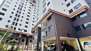 Un edificio residenziale a più piani con un garage e un'area verde piantumata.