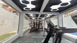 Una palestra con attrezzature per esercizi, un tapis roulant e motivi luminosi esagonali su soffitto e pavimento.
