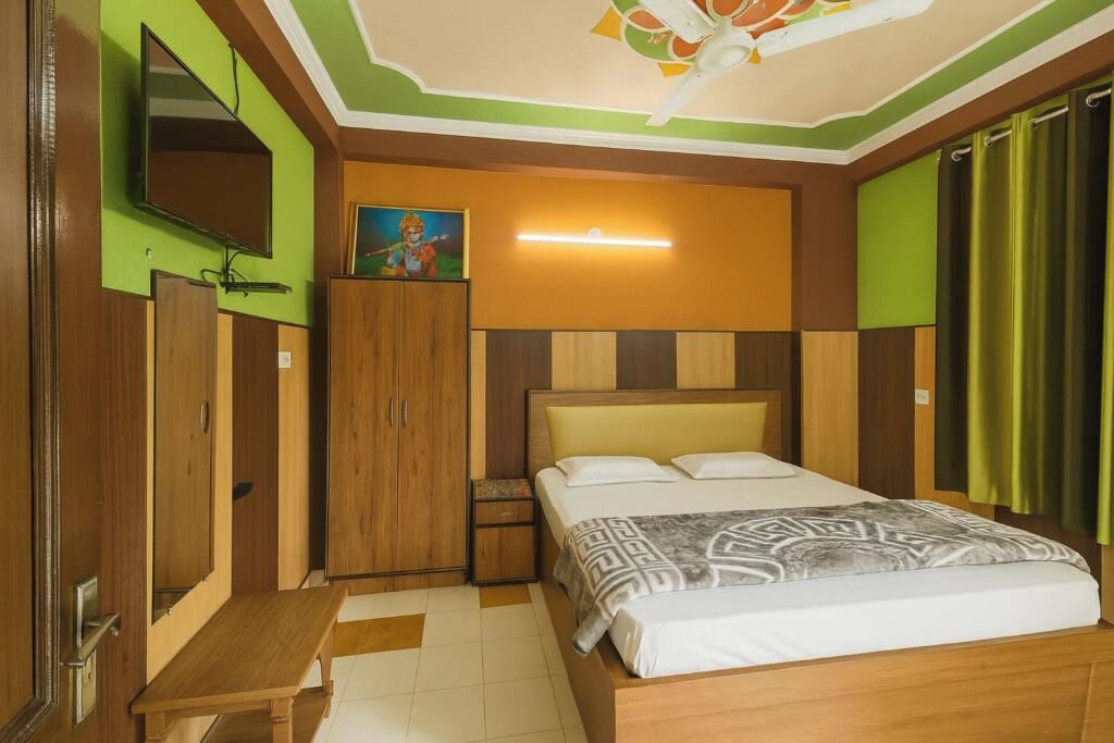 A bedroom with a bed, a wardrobe, a bench, a TV, and a ceiling fan.