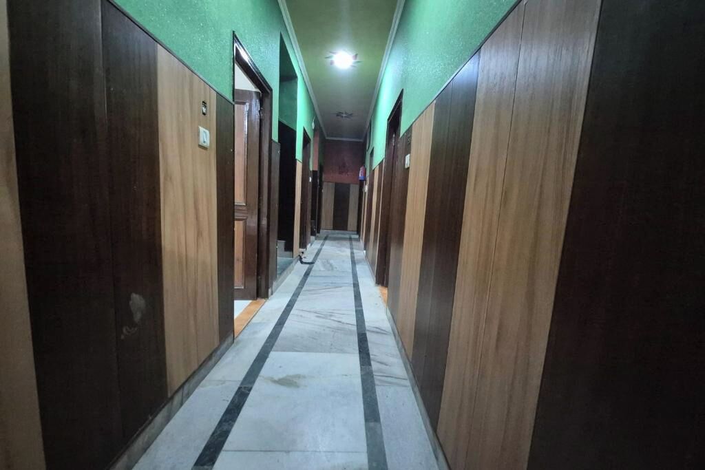 A corridor with wooden doors, a tiled floor, and a green wall.