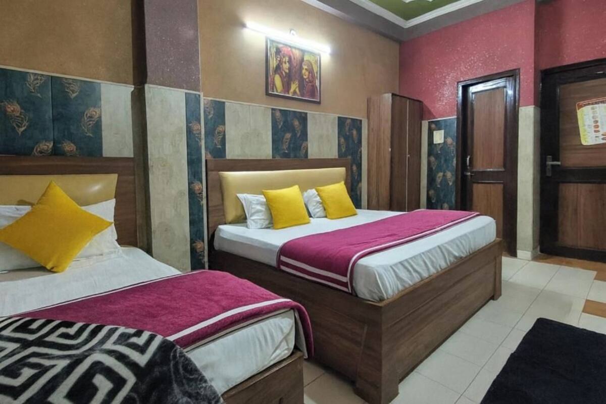 A hotel room with two beds, a wooden headboard, a wall with a decorative pattern, and a door with a poster.