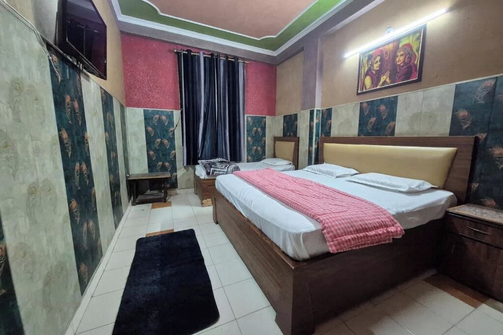 A bedroom with a bed, a nightstand, a desk, a chair, a window with curtains, and a painting on the wall.