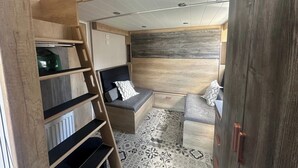 Quarto compacto e bem iluminado com uma cama beliche, um pequeno espaço para sentar e um chão estampado.