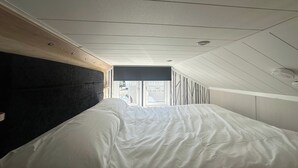 Um quarto com uma cama, uma janela e teto com iluminação embutida.