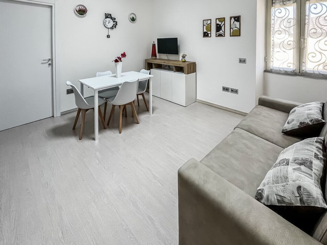 Un ambiente compatto con angolo ristoro, divano e televisione.