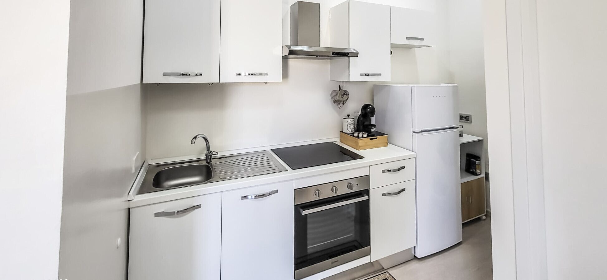 Eine kleine Küche mit Spüle, Herd, Backofen und Kühlschrank.