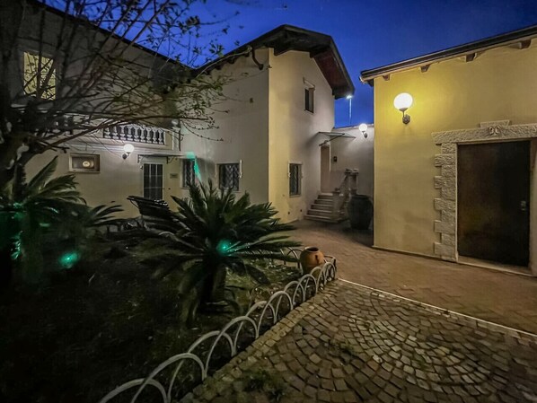 Un patio con un sendero empedrado, una palmera y un edificio con entrada de piedra.