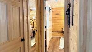 Un pasillo interior de madera con una cama, una mesita de noche y un perchero en la pared.