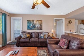 A living room with a brown leather sofa, a wooden coffee table, a painting on the wall, and a ceiling fan. - Escape to the serene beauty of Gatlinburg with Mountain View Memories Unit #2102 (Gatlinburg)