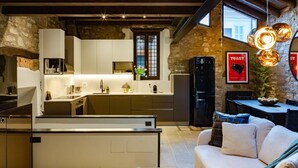Une cuisine moderne dotée d’un îlot central, de murs en pierre et d’un coin repas avec un canapé.
