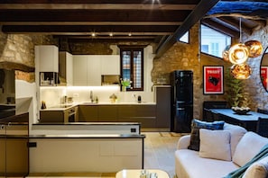 A modern kitchen with a central island, stone walls, and a dining area with a sofa. - Loft 15 Torno Lake Como (TORNO)