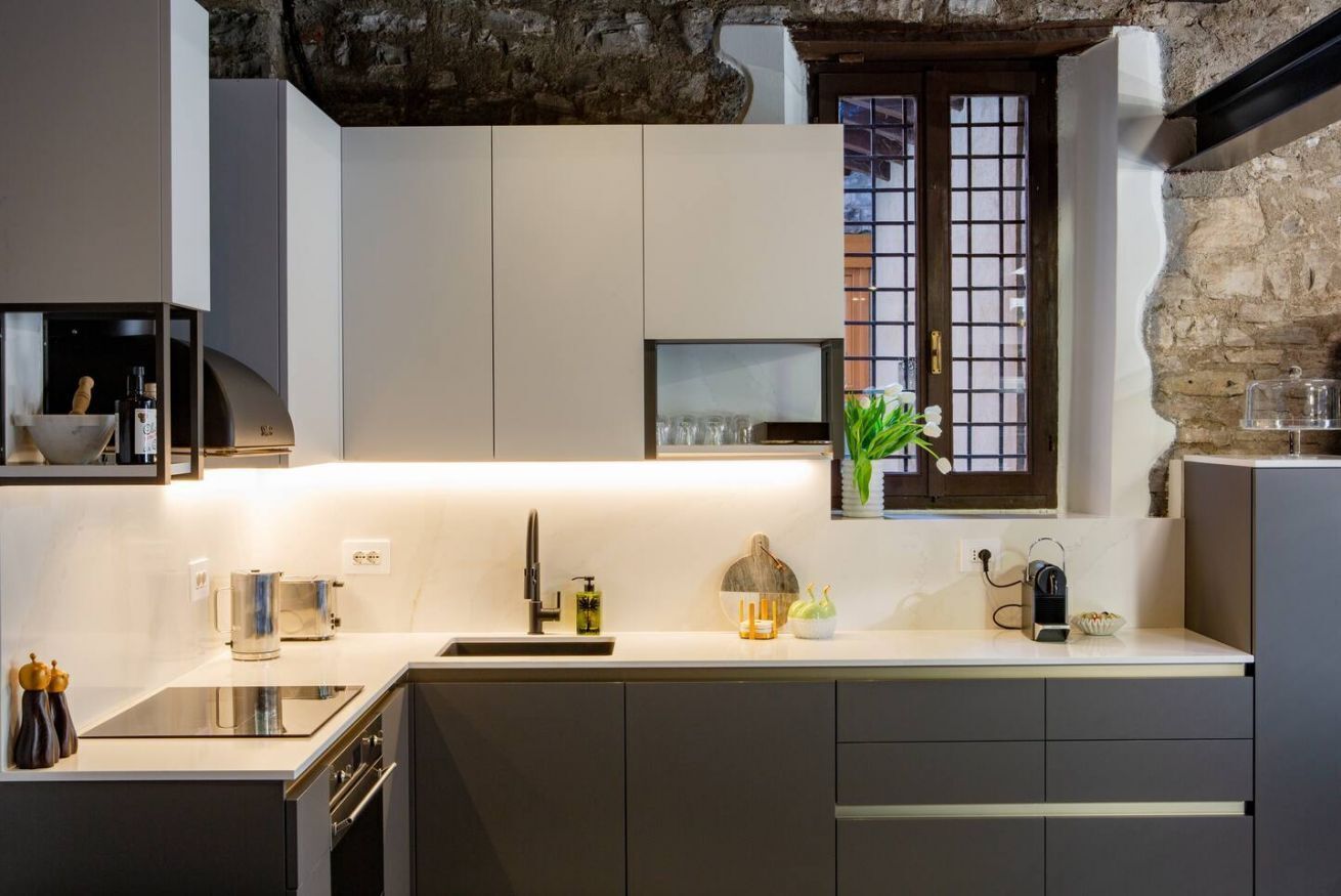 Una cucina moderna con una parete in pietra, una finestra con griglia e un forno a incasso.