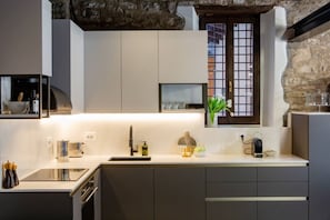 A modern kitchen with a stone wall, a window with a grid pattern, and a built-in oven. - Loft 15 Torno Lake Como (TORNO)