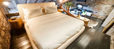 Un dormitorio con una cama grande, vigas de madera, paredes de piedra y un ambiente rústico.