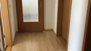 Ein Flur mit Holzboden, einer Milchglasschiebetür und einer schlichten Wand.