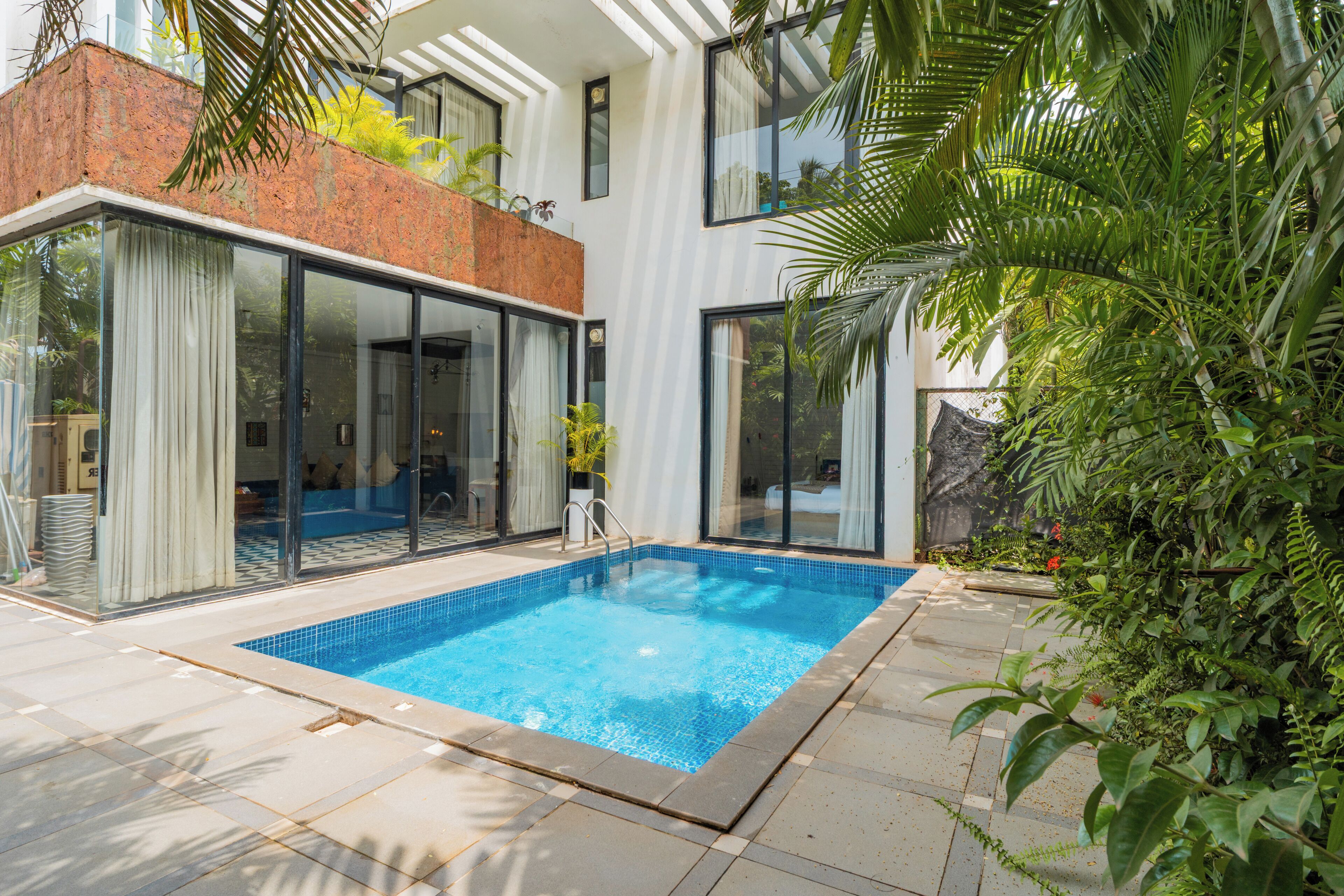 A modern house with a swimming pool, large glass doors, and a brick exterior.