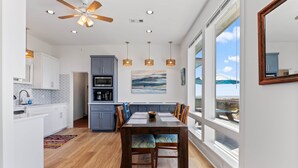 A modern kitchen with grey cabinets, a wooden dining table, and a ceiling fan. - Driftwood Beach House: Your Perfect Getaway in Matagorda (Matagorda)