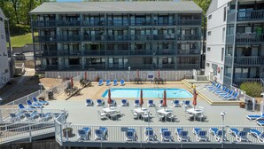 A hotel with a swimming pool, multiple balconies, and outdoor seating areas.
