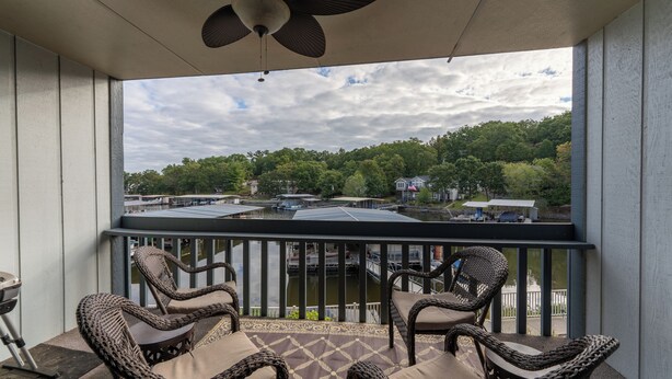 A balcony with wicker chairs and a view of a dock and boats.