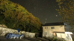 Ein Haus mit einer Steinmauer, einem überdachten Sitzbereich und einem Sternenhimmel.