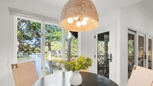 A dining area with a round table, chairs, a white vase with greenery, and a woven light fixture. - Stunning remodeled Turtle Cove (Kiawah Island)