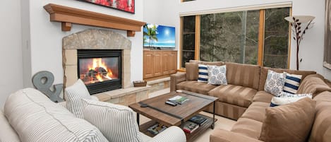 A living room with a fireplace, a sofa, a coffee table, and a television.