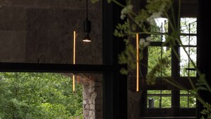 A dining area with a table set for two, a brick wall, and a view of greenery outside. - Moulin Moulin (Dannes)