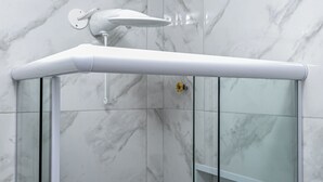 A modern bathroom with a glass shower enclosure, white marble walls, and a white showerhead. - Largo do Machado Metrô Aterro do Flamengo (Rio de Janeiro)