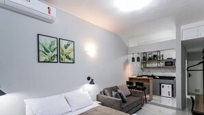 A modern room with a bed, a sofa, a small kitchen area, and a wall-mounted air conditioner. - Largo do Machado Metrô Aterro do Flamengo (Rio de Janeiro)