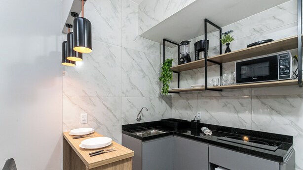 A modern kitchen with a built-in microwave, a sink, and a wooden countertop. - Largo do Machado Metrô Aterro do Flamengo (Rio de Janeiro)