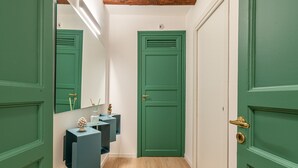 A hallway with green doors, a wooden floor, and a mirror on the left wall. - Palazzo Ferrara - Clementina by Wonderful Italy (Palermo)