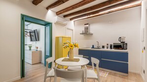 A modern kitchen with a yellow refrigerator, white dining table, and blue cabinets. - Palazzo Ferrara - Clementina by Wonderful Italy (Palermo)