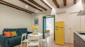 A compact living space with a sofa, dining table, chairs, a yellow refrigerator, and a kitchen area. - Palazzo Ferrara - Clementina by Wonderful Italy (Palermo)