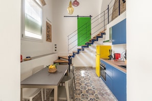 A kitchen with a staircase, a dining table with chairs, and a yellow appliance. - Palazzo Ferrara - Loft With Private Garden by Wonderful Italy (Palermo)