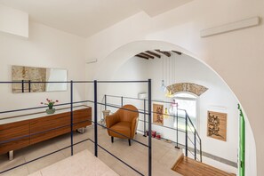 A modern interior with a wooden bench, a brown leather chair, and a staircase with a green door. - Palazzo Ferrara - Loft With Private Garden by Wonderful Italy (Palermo)