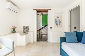 A modern interior with a bed, a chair, a dining area, and a staircase leading to a green-lit room. - Palazzo Ferrara - Loft With Private Garden by Wonderful Italy (Palermo)