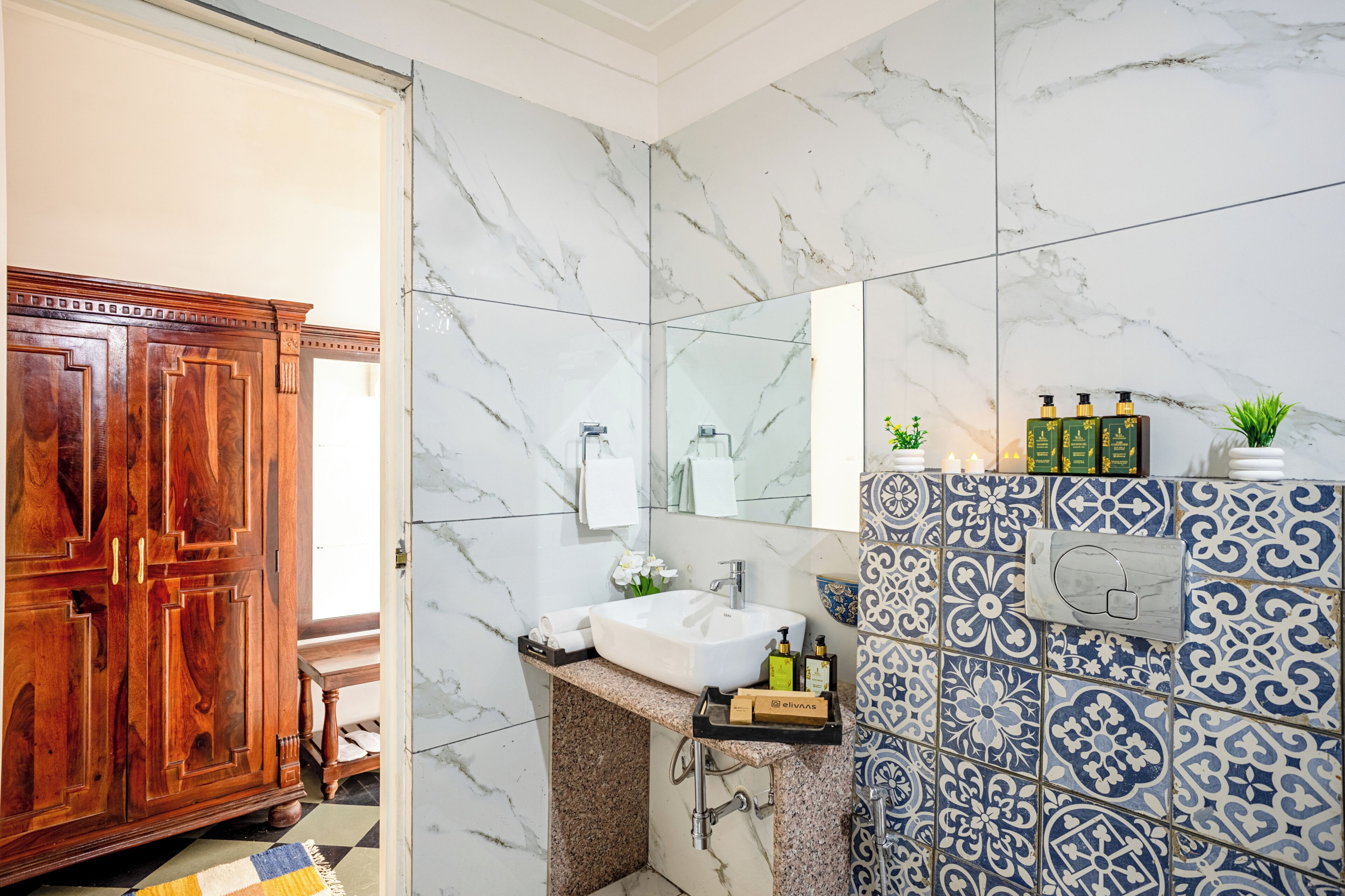 A bathroom with a marble wall, a wooden cabinet, a sink, and a mirror.