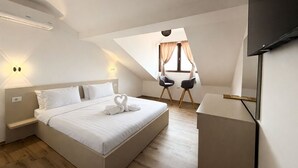 Ein modernes Hotelzimmer mit einem großen Bett, einem Schreibtisch und einem Fernseher.