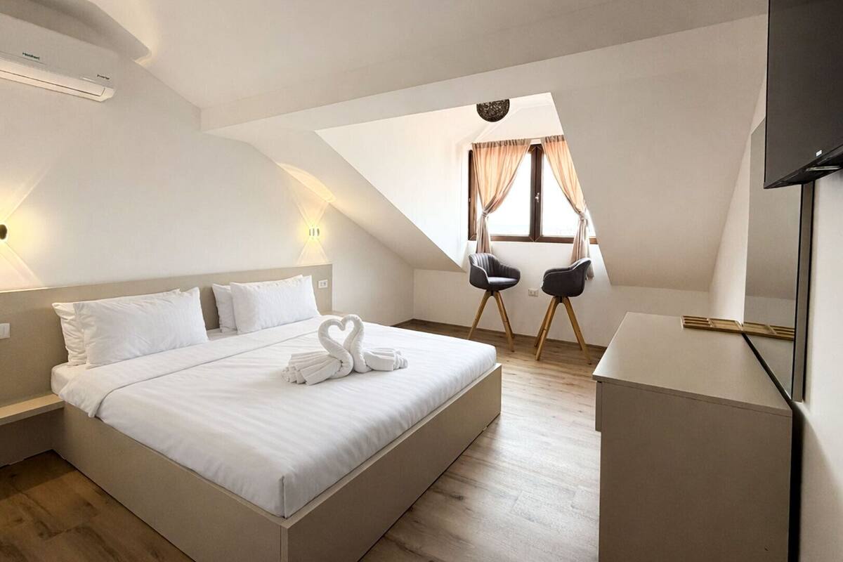 A modern hotel room with a large bed, a desk, and a TV.
