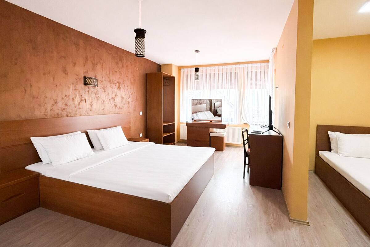A hotel room with a large bed, a desk, and a chair.