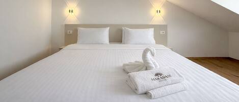 Een hotelkamer met een bed, twee wandlampen en een handdoek met de naam van het hotel.