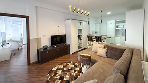 Ein modernes Wohnzimmer mit einer Couch, einem Fernseher und einem Essbereich mit Stühlen.